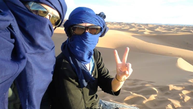 We are shrouded in blue cloth in the Sahara Desert, one of our slow travel destinations in early retirement.